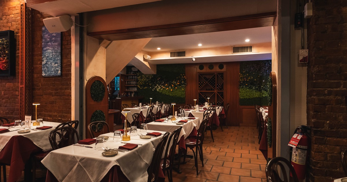 Cozy restaurant interior with warmly lit dining tables set with white tablecloths