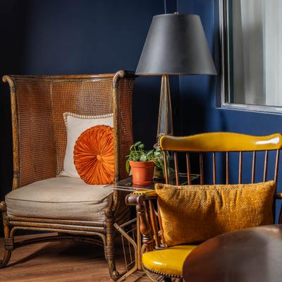 Chairs with pillows, glass table, a potted plant, and a lamp.