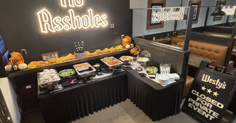 Buffet setup with chafing dishes and decorations, alongside a neon signage