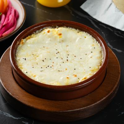 Baked melted cheese in a clay dish.