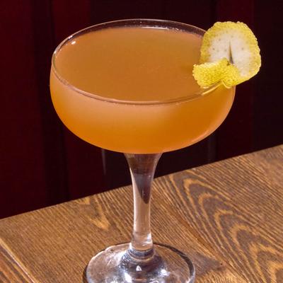 Bees Knees cocktail garnished with a lemon twist.