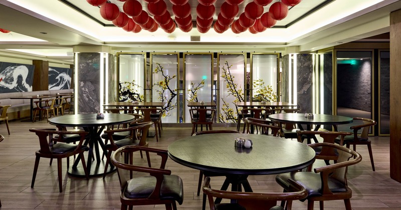 Interior, red lanterns, round wooden tables, and decorative panels with yellow blossoms
