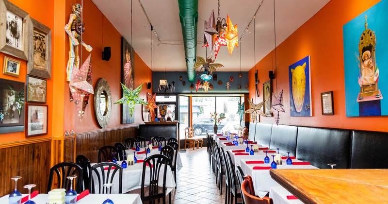 Restaurant interior with orange walls, star-shaped decorations, mixed art, and set tables