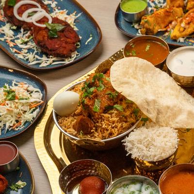Indian biryani thali with chicken biryani, papadum, curries, rice, and chutneys.