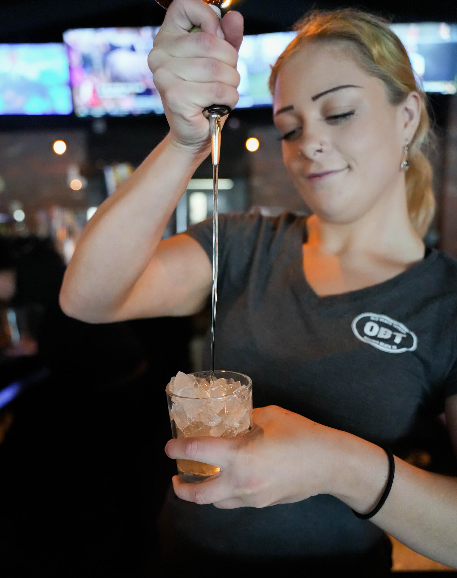 Bartender pouring a cocktail in an iced glass