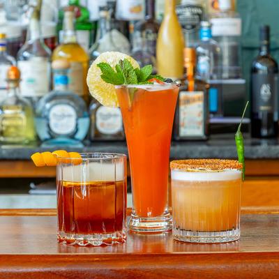 Three vibrant cocktails on a bar counter.