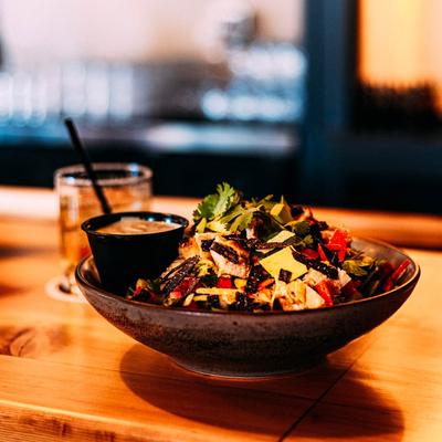 Chicken taco salad served with dressing on the side, alongside a cocktail.
