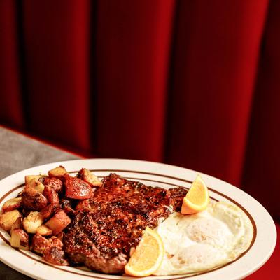 Grilled steak served with eggs and potatoes.