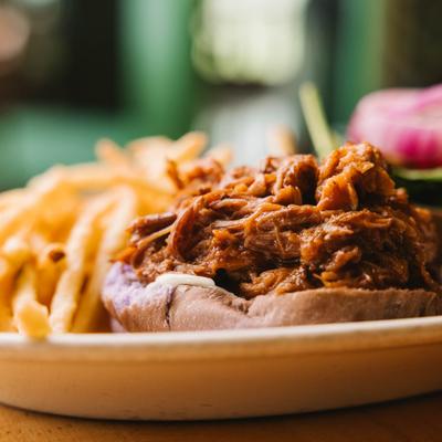 Pulled pork sandwich with fries on plate.