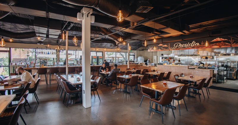 Interior, diner area, tables, chairs, people seating, bar behind, kitchen by side
