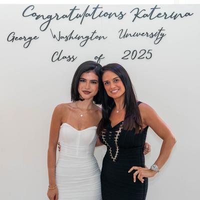 Two guests posing by a celebratory event sign.