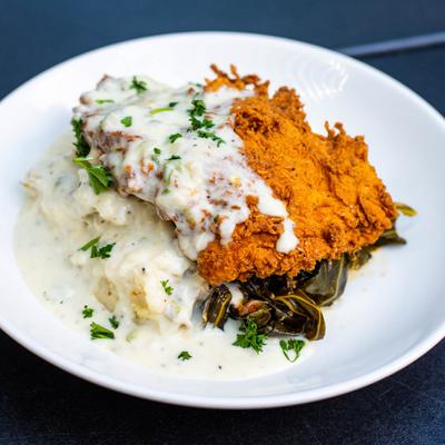 chicken fried chicken steak with mashed potatoes and collard greens.