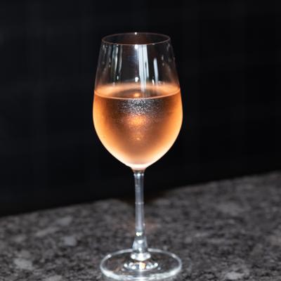 A glass of rosé on a textured marble surface with a dark background.