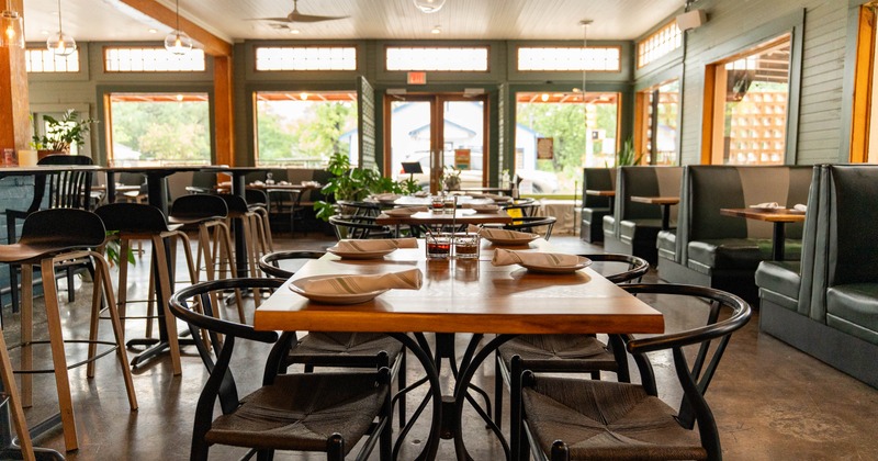 A cozy restaurant interior featuring wooden tables set with plates and napkins