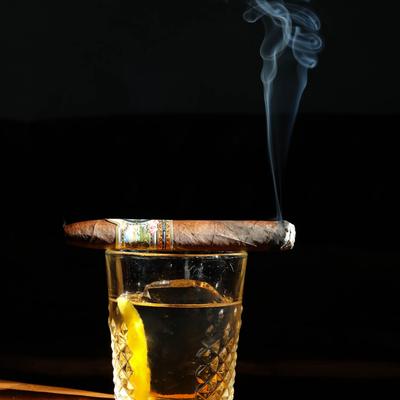 Lit cigar on top of a glass of Sazerac
