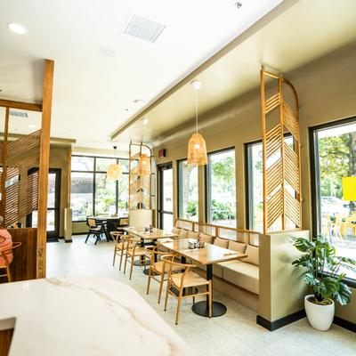Modern cafe interior with wooden accents, pendant lights, and large windows overlooking greenery.