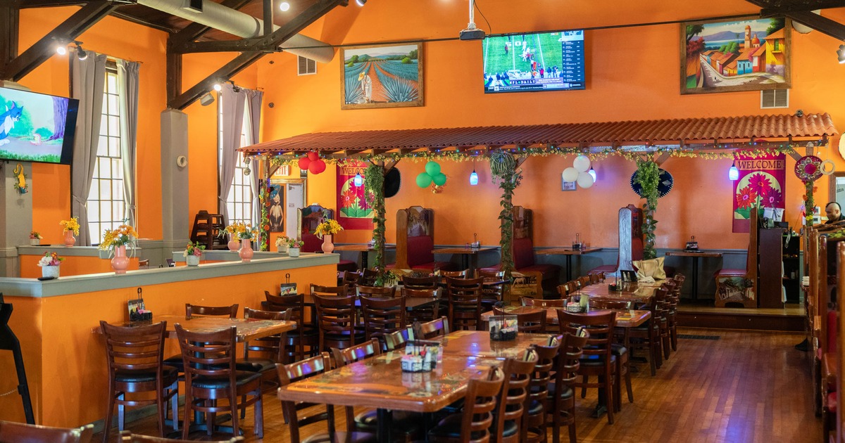 Interior of a colorful restaurant with orange walls, wooden tables, and decorative elements