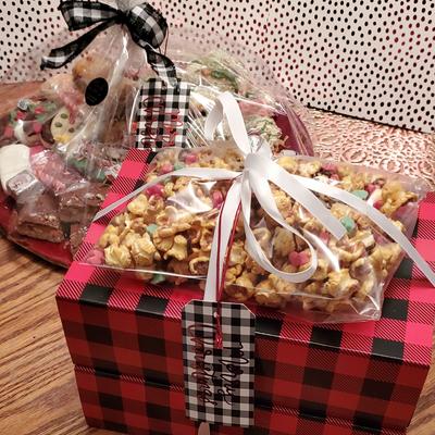 Red and black plaid gift boxes with bows and holiday treats on a wooden surface.
