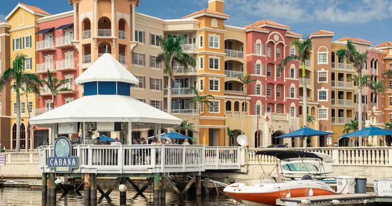 Waterfront bar with colorful buildings and palm trees in the background