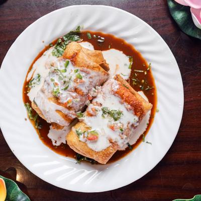 Chimichangas with red salsa and cheese sauce.