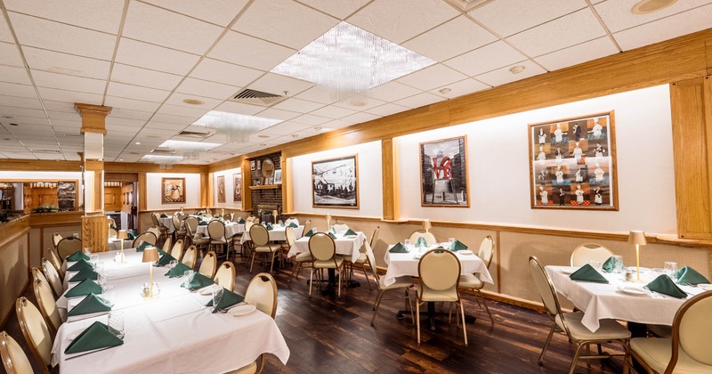 Spacious restaurant dining room with white tablecloths, green napkins, tan chairs