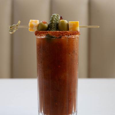 Bloody Mary, garnished with skewered olives, cheese cubes, and pickles.