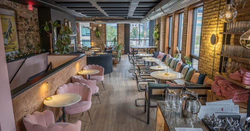 Inside, pink and metal seating, large windows, and exposed brick walls