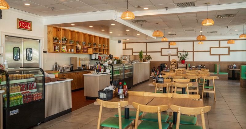 Interior - wooden tables & chairs, a service counter, pendant lights, green-accented seating