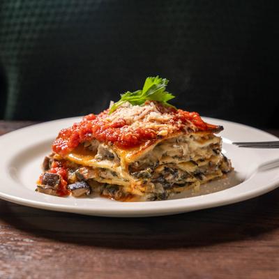 Layered lasagna with tomato sauce, cheese, and spinach, served on a white plate.