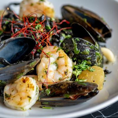 Squid ink pasta with mussels and shrimp on a plate.