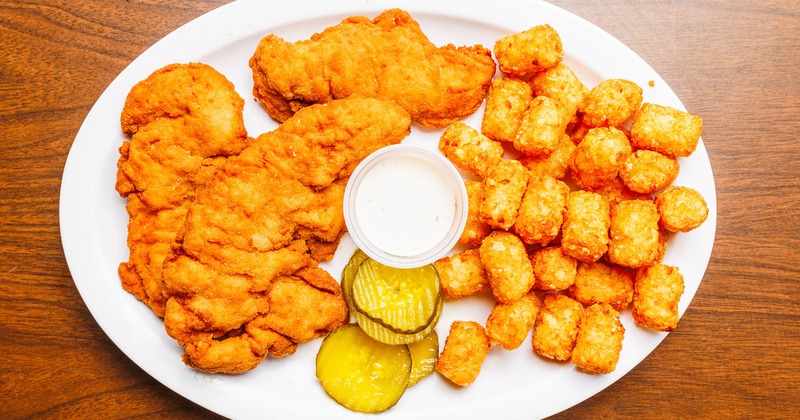Chicken tenders with tater tots, pickles, and dipping sauce