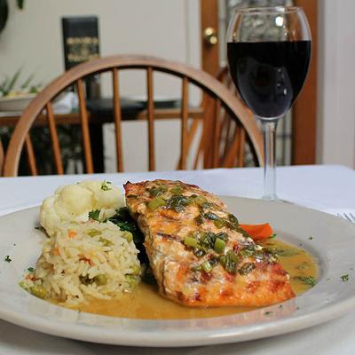 Grilled salmon with orange-ginger-scallion sauce, served with vegetable rice and wine.