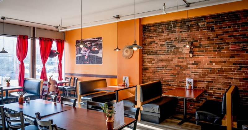 Interior - orange and red brick walls, black booths, wooden tables, red curtains, pendant lighting