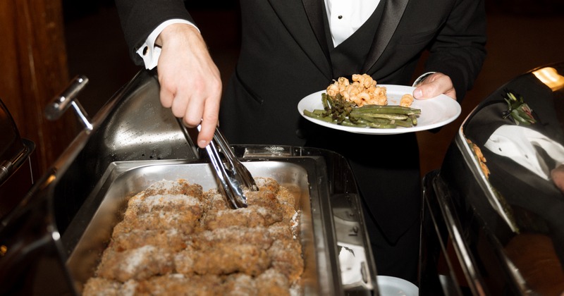 A person serving food at a buffet