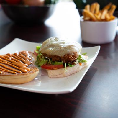 Fried chicken sandwich, with cheese, tomato, lettuce, and spicy sauce.