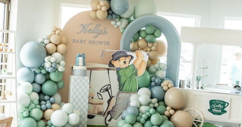 Golf-themed baby shower display with balloons and cartoon golfer cutout