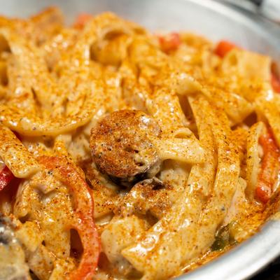Creamy pasta with sausage and peppers, close up view.