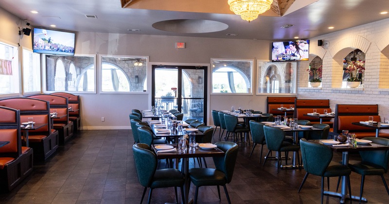 Interior of a restaurant with booths, tables, a chandelier and televisions