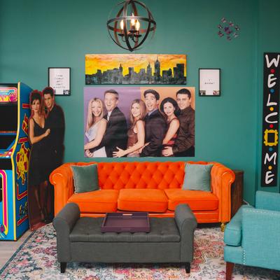 Lounge area with couches and armchairs, an arcade machine and posters on a wall.