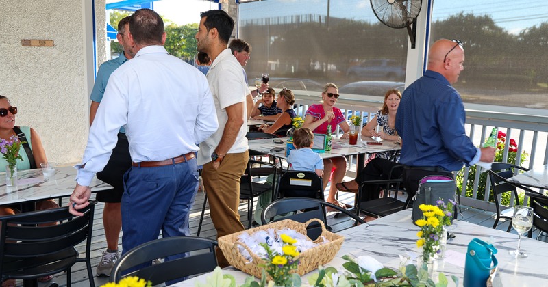 Group of people gathering and dining on a restaurant's outdoor patio