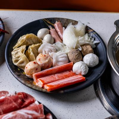 Variety of common hot pot ingredients featuring raw seafood, dumplings, and meatballs.