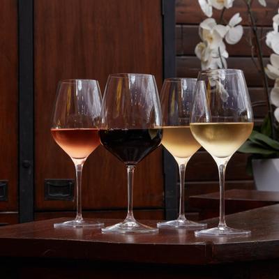 Four glasses of assorted wine arranged  on a table.