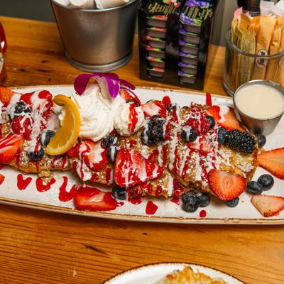 Concha French Toast topped with whipped cream, berries, icing and a flower.