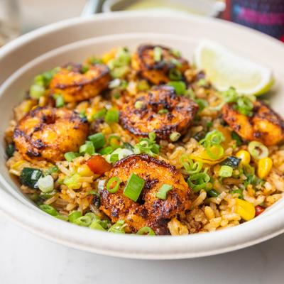 Grilled shrimp rice bowl topped with scallions and lime.