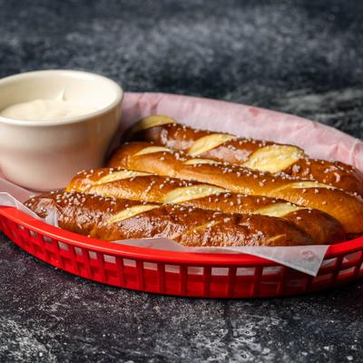 Pretzel sticks served in a basket with a creamy dipping sauce.