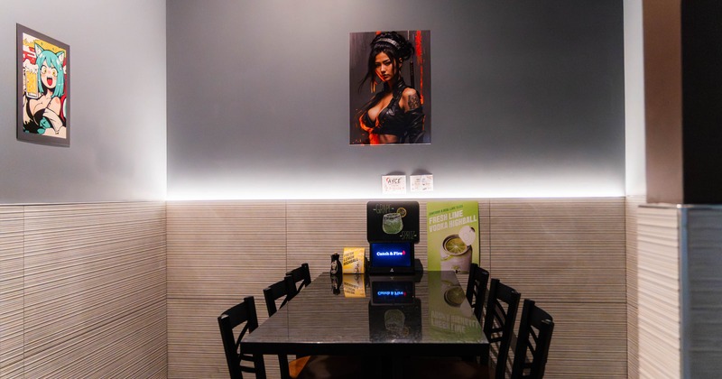 A restaurant corner - a black table surrounded by chairs, colorful character artwork on the wall