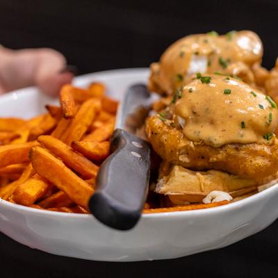 Chicken and waffles served alongside sweet potato fries.