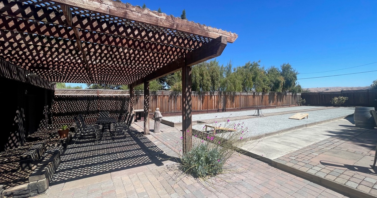 This is our back patio that has two bocce ball courts. There is also a wooden trellis over a paved area for seating.