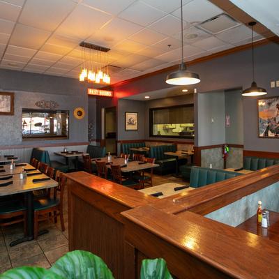 Cozy restaurant interior with teal booths, wooden tables, and hanging lights.