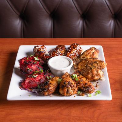 Platter of assorted chicken wings with a dipping sauce.